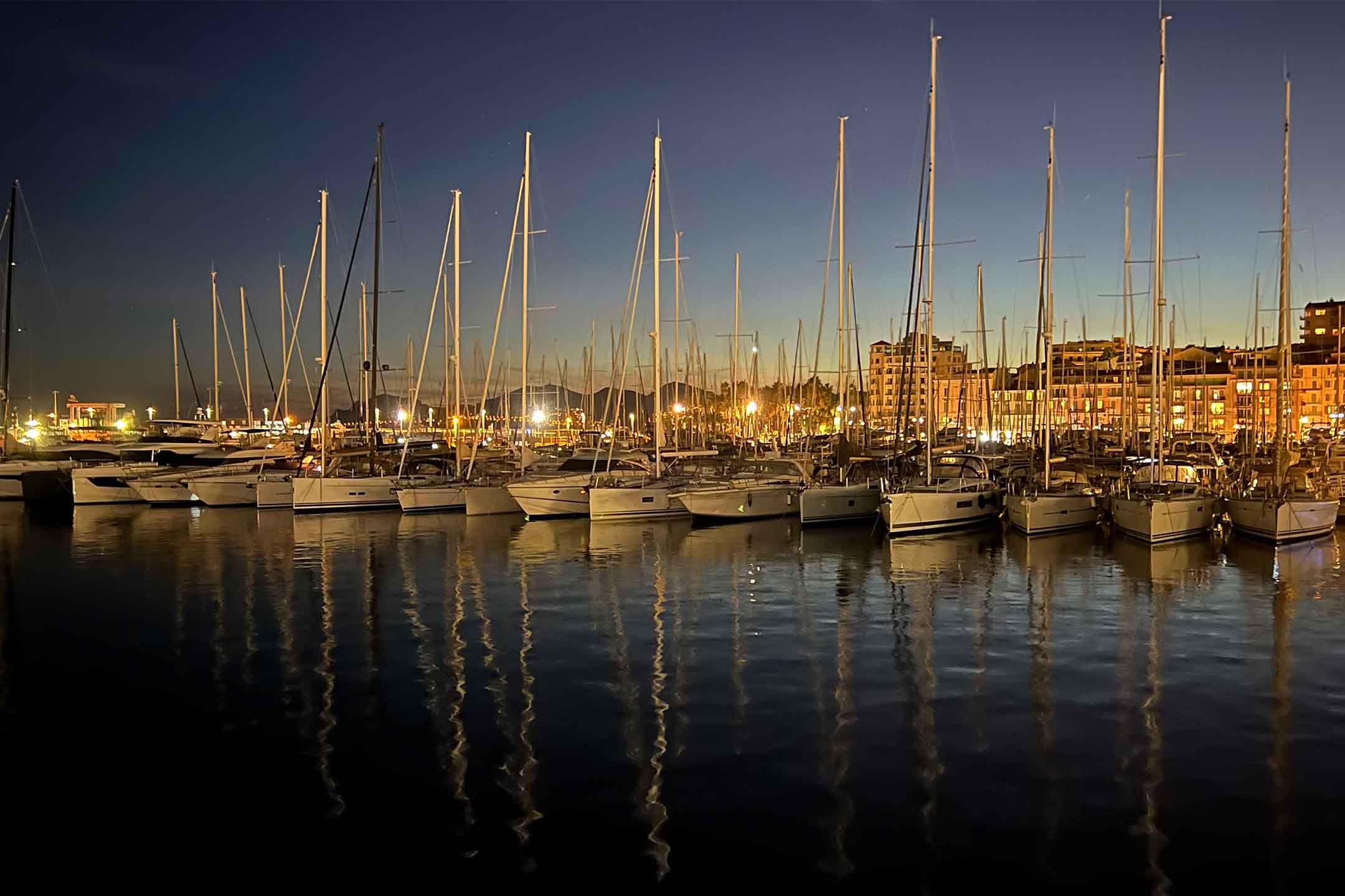 Photos of yachts in the port of Cannes, France with the evening sun set in the background.